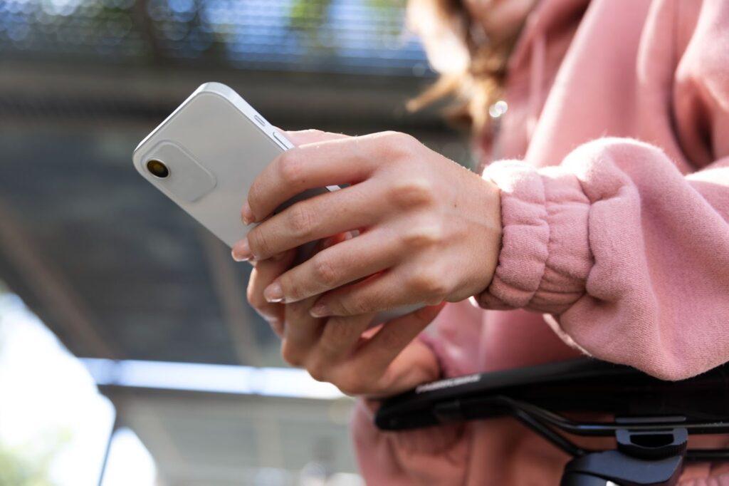 a woman in a pink jumper holding a white phone in her hands