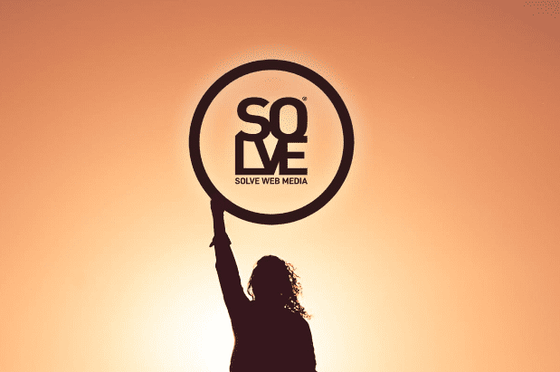 girl standing in the orange sun holding a solve web media logo